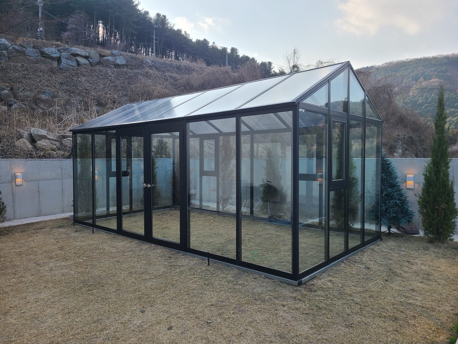 산을 배경으로 완성된 검정 프레임 소형온실